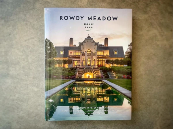 Book cover featuring an illuminated estate house at twilight with a reflecting pool. Rowdy Meadow: House, Land, Art.