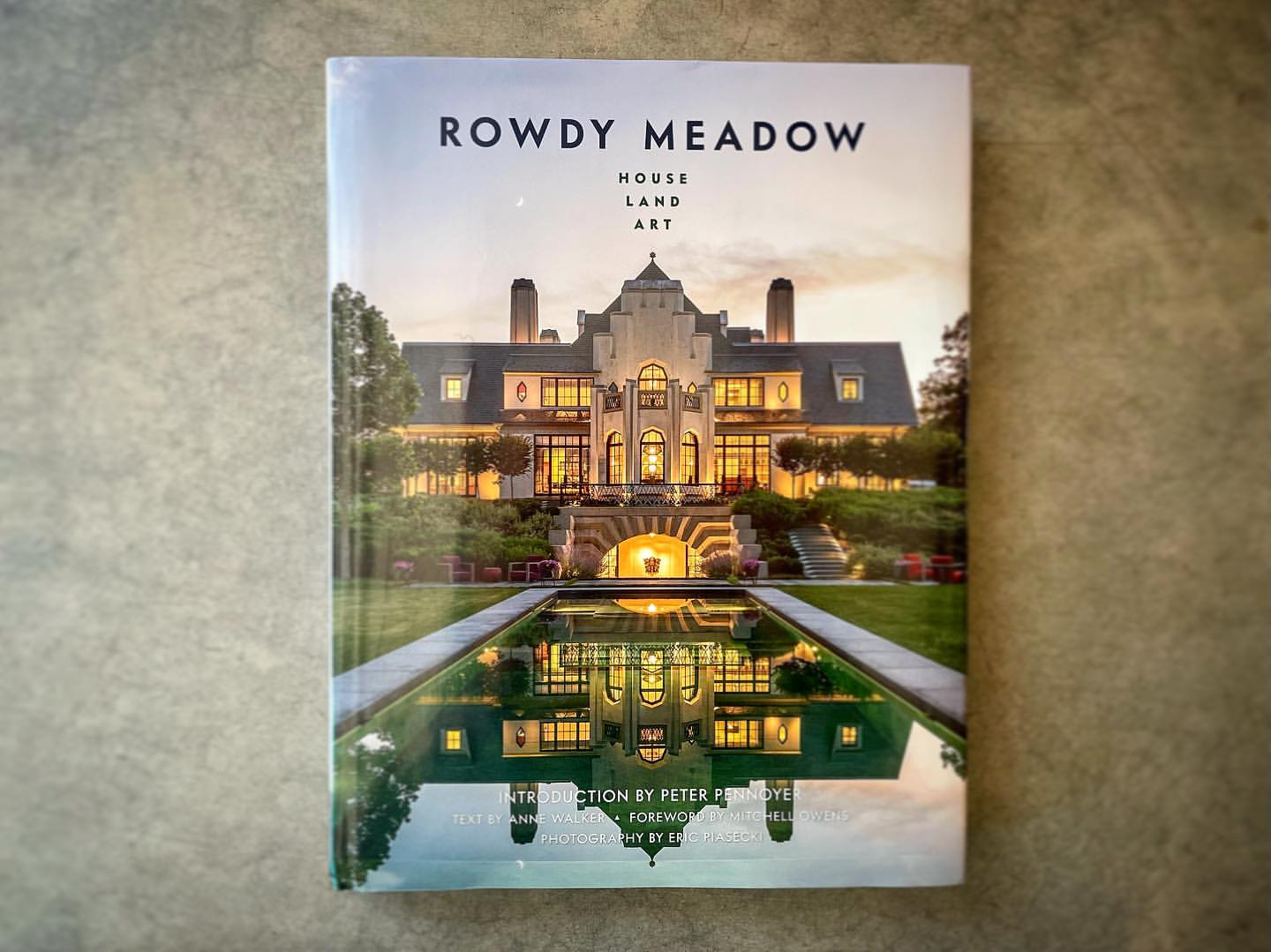 Book cover featuring a photograph of the Rowdy Meadow estate at dusk. The building and its reflection in the water are visible.