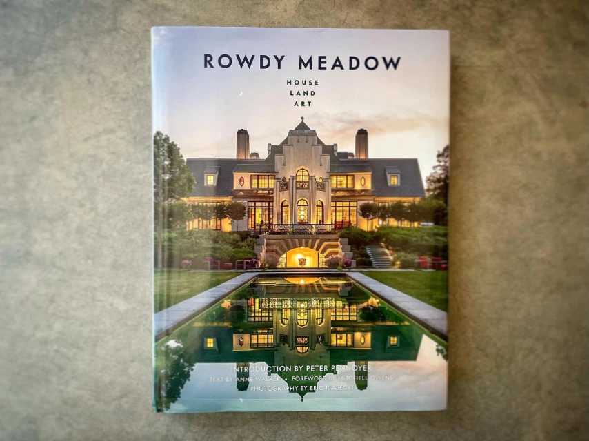 Book cover featuring a photograph of the Rowdy Meadow estate at dusk. The building and its reflection in the water are visible.
