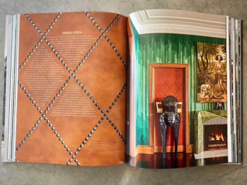 Open book shows two interior designs: one a brown leather studded dining room, the other a green paneled room with red door.