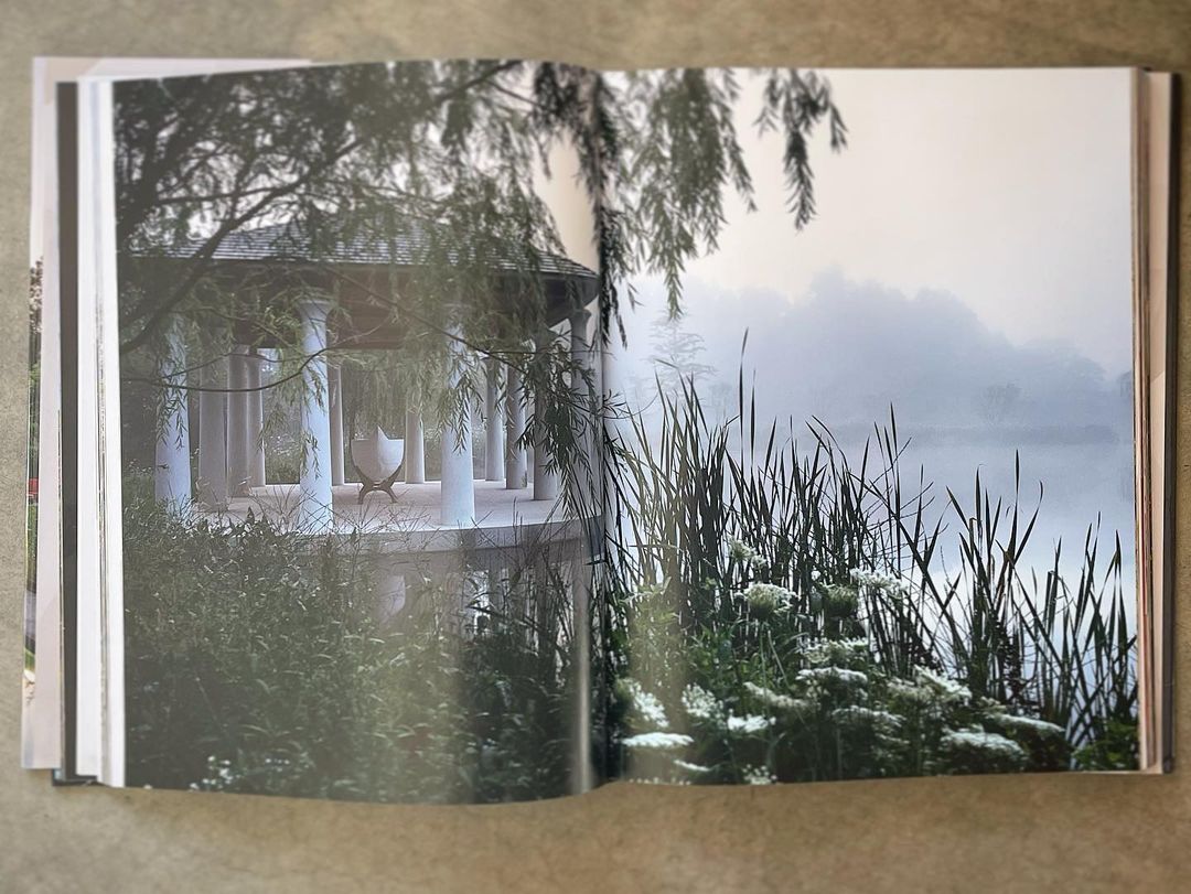 Open book displays an architectural landscape featuring a gazebo with columns, lush greenery, and a misty lake in the background.