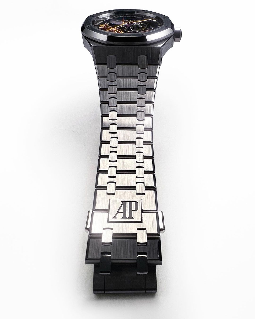 Close-up of a black and silver Audemars Piguet Royal Oak watch with an open-worked dial, set against a clean, white background.