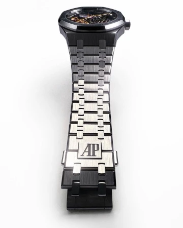 Close-up of a black and silver Audemars Piguet Royal Oak watch with an open-worked dial, set against a clean, white background.