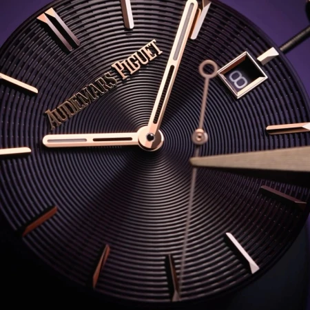 Close-up of a luxury Audemars Piguet wristwatch featuring a black textured dial, rose gold hands and hour markers, and date window.