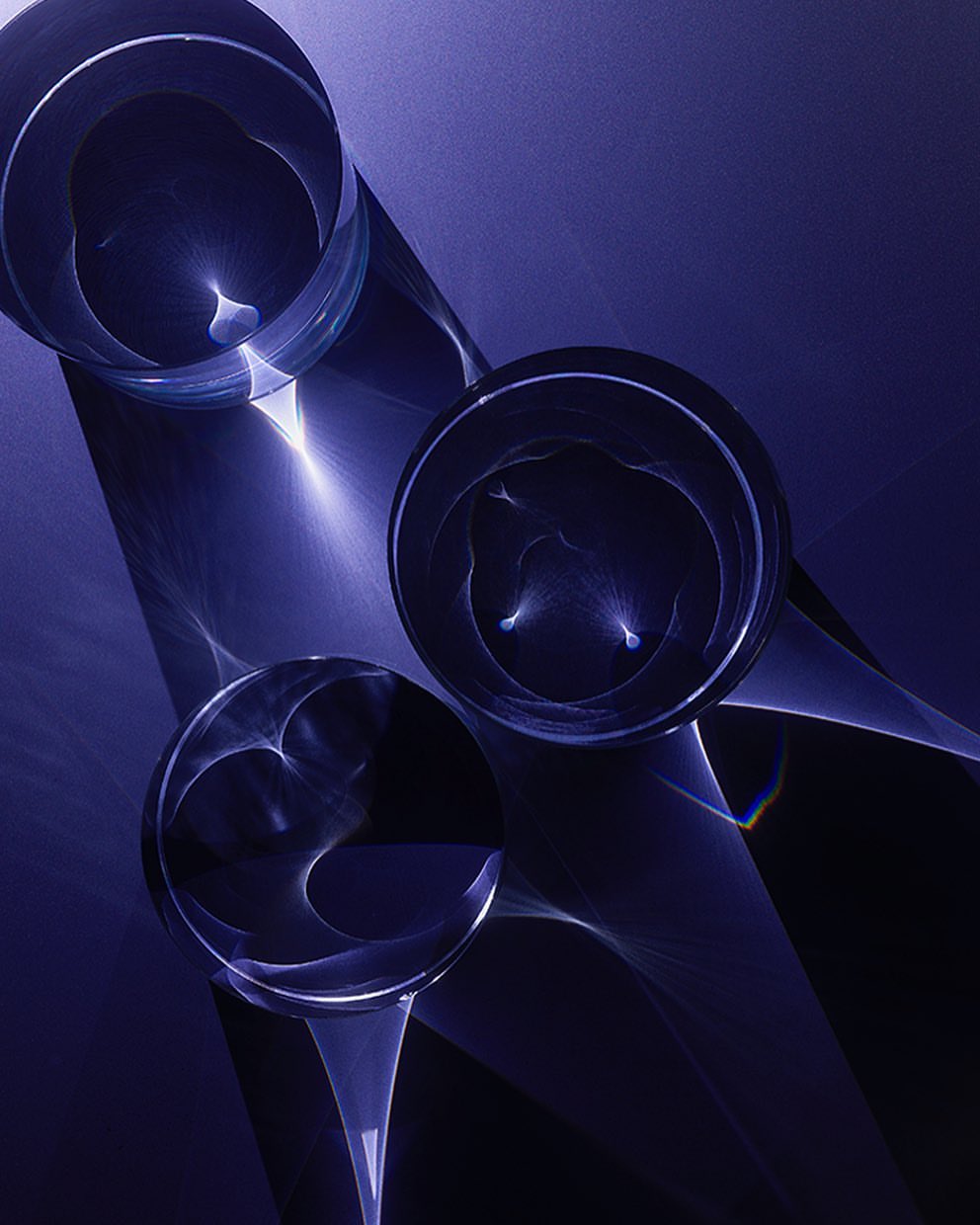 Abstract composition featuring three clear glass spheres casting light reflections against a gradient blue background, emphasizing luminosity.