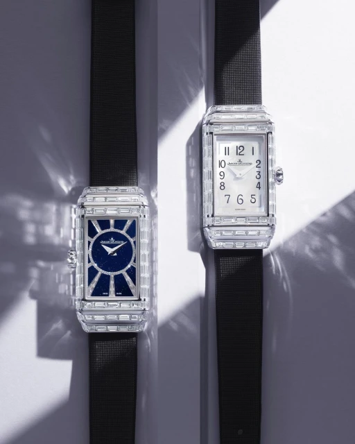 Two luxury rectangular timepieces with gemstone bezels and dark straps are displayed on a light surface with soft lighting.