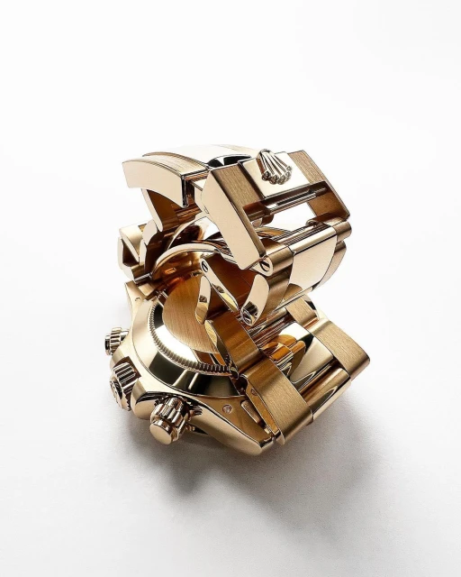 High-angle shot of a gold Rolex watch with a metal strap, showcasing its intricate design and luxurious appeal against a white backdrop.