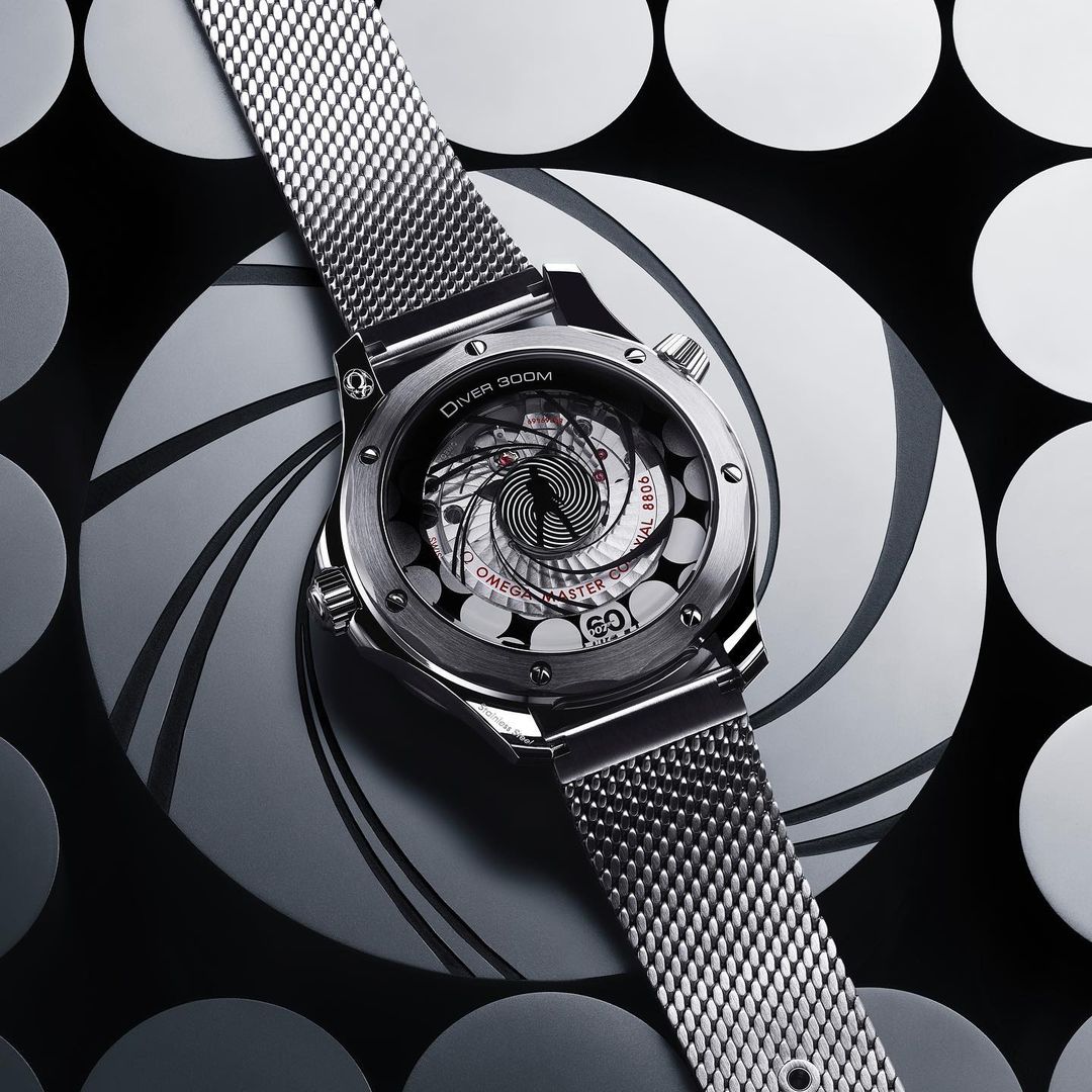Elevated view of a silver Omega Seamaster Diver 300M watch with a metal band, displayed against a black and white patterned backdrop.