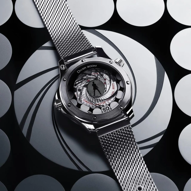 Elevated view of a silver Omega Seamaster Diver 300M watch with a metal band, displayed against a black and white patterned backdrop.