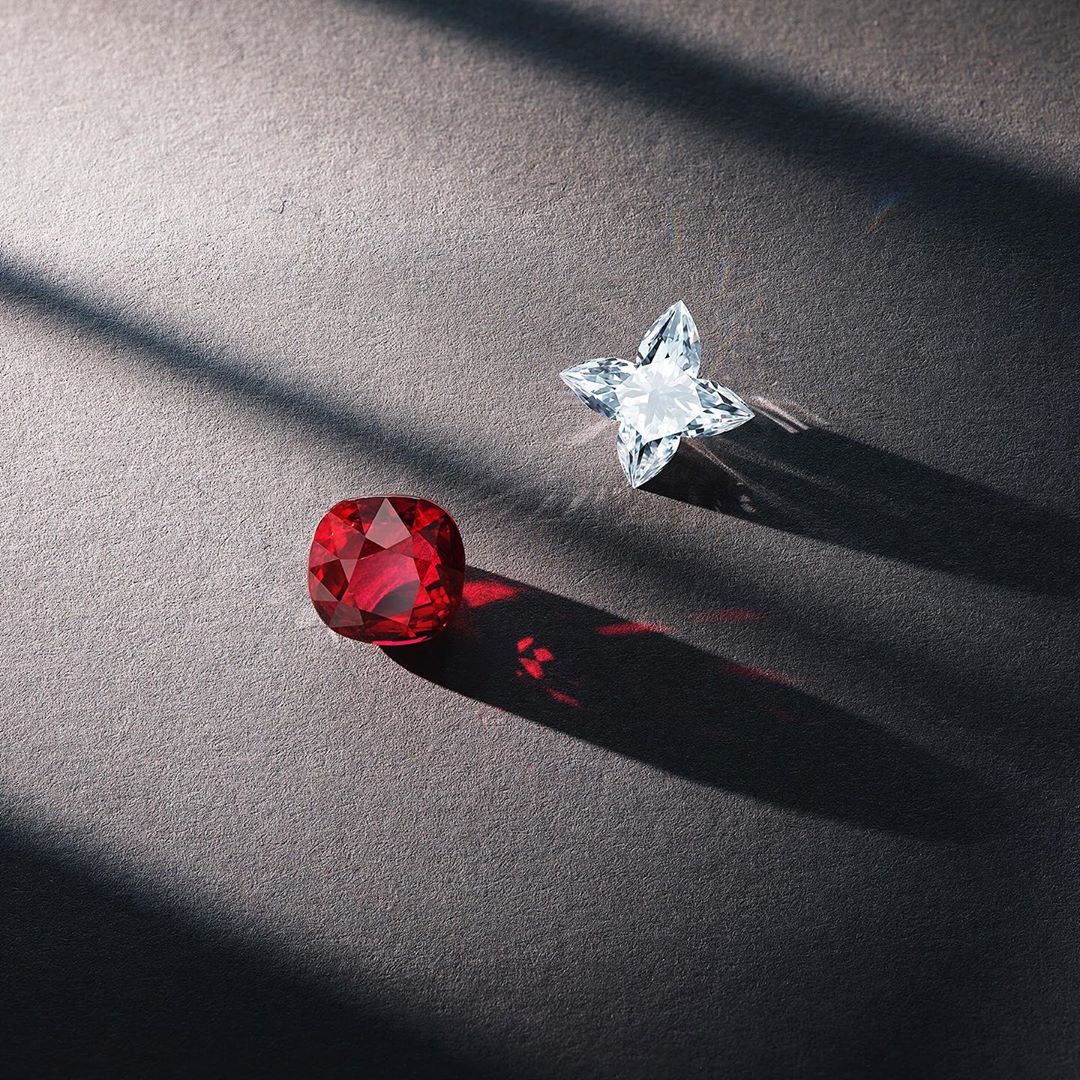Cushion-cut ruby gemstone and star-cut white sapphire on dark gray surface with strong light and shadows, ideal for jewelry design.
