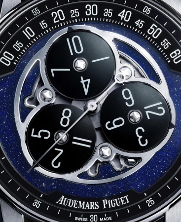 Close-up of an Audemars Piguet watch face with multiple dials and silver mechanics against a blue and black speckled background.