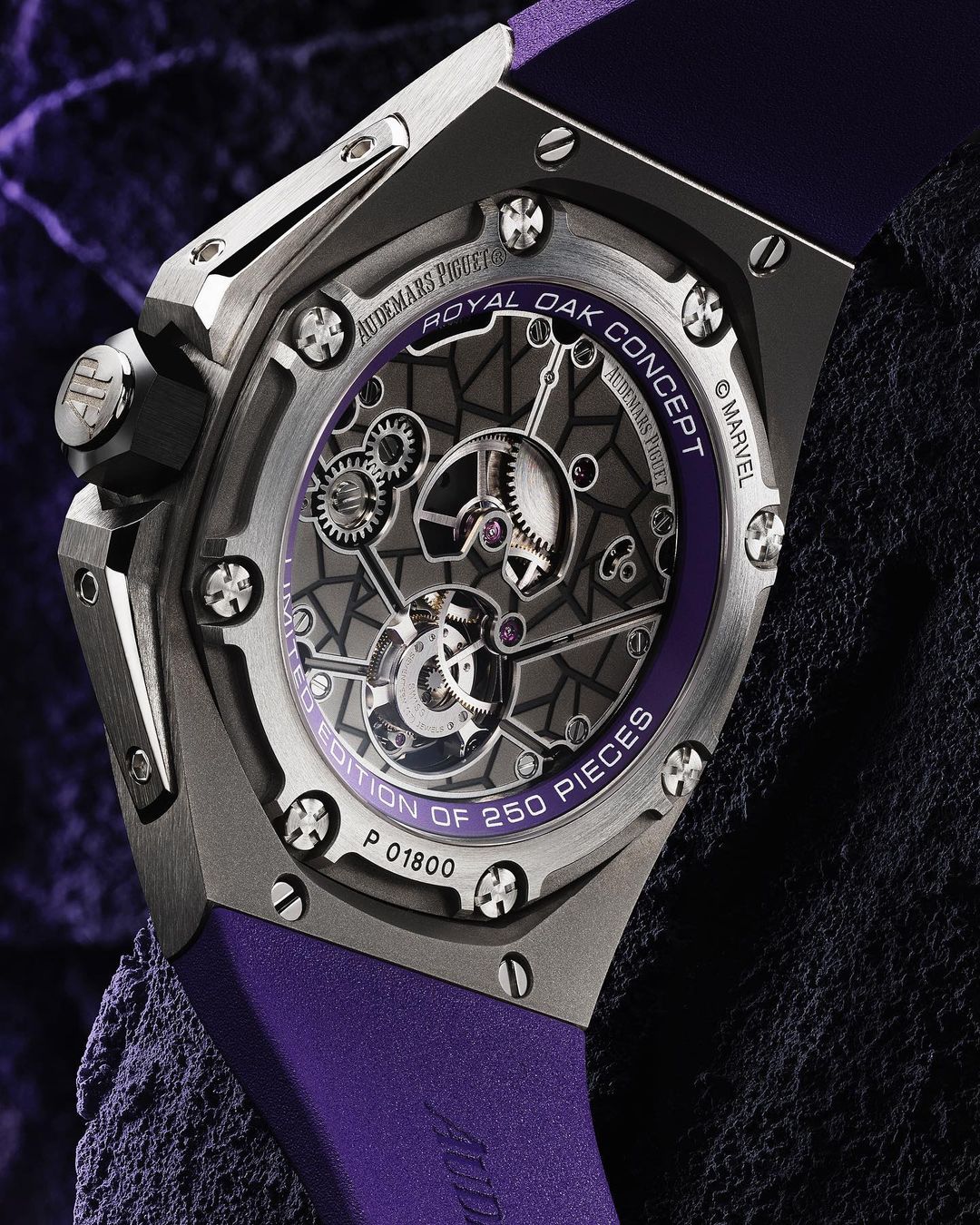 Close-up of an Audemars Piguet Royal Oak Concept watch with a purple band, revealing intricate inner mechanisms against a dark textured backdrop.