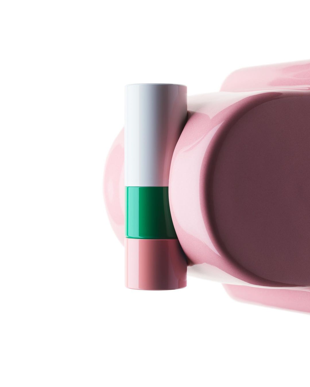 Close-up of a pink makeup compact sitting next to a white, green, and pink tube of lip balm on a white background.