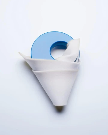 Still life photograph of stacked white ceramic coffee filters with a blue plastic holder on a white background, studio lighting.