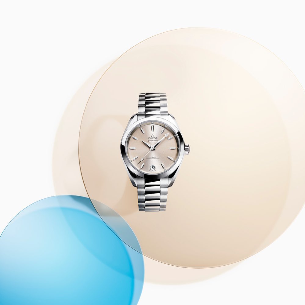 Silver Omega Seamaster Aqua Terra wristwatch with stainless steel bracelet against transparent peach and blue spheres on white.
