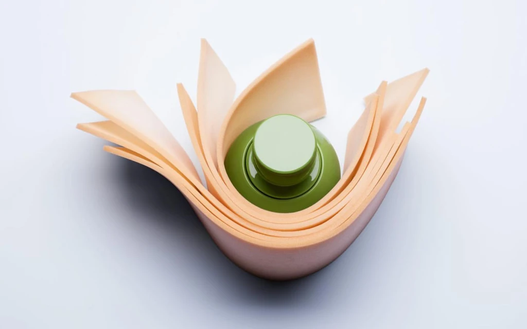 Green bottle surrounded by curved tan paper, close-up product shot on white backdrop, soft lighting, promoting beauty or healthcare product.
