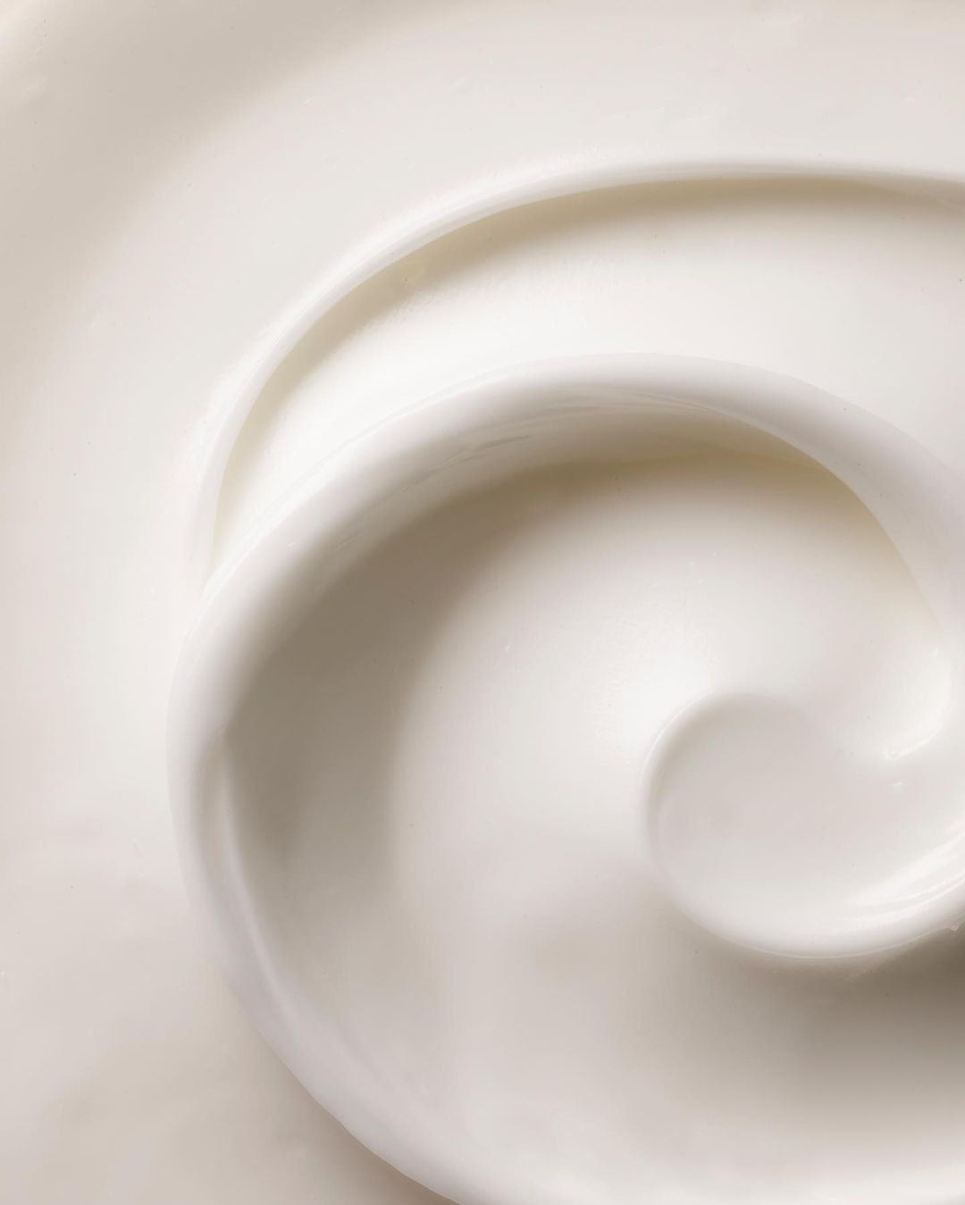 Swirl of white cream, lotion, or cosmetic product filling the frame, showcasing its smooth texture and creamy appearance.