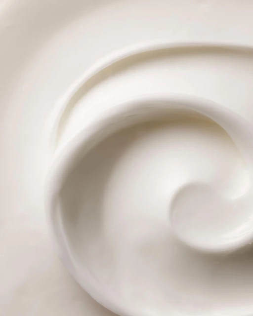 Swirl of white cream, lotion, or cosmetic product filling the frame, showcasing its smooth texture and creamy appearance.