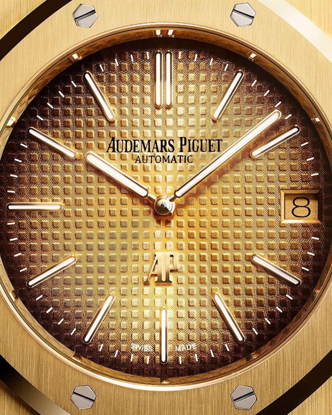 Close-up shot of a gold Audemars Piguet automatic wristwatch with a textured dial, gold hands, and visible brand logo.