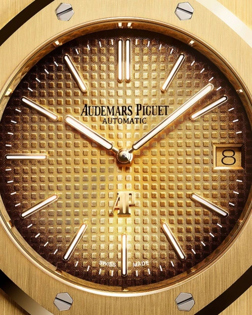 Close-up shot of a gold Audemars Piguet automatic wristwatch with a textured dial, gold hands, and visible brand logo.
