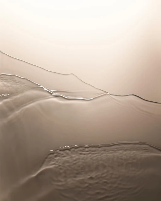 Abstract image of liquid with a glossy surface, featuring warm, neutral tones with textured ripples and a gradient background.