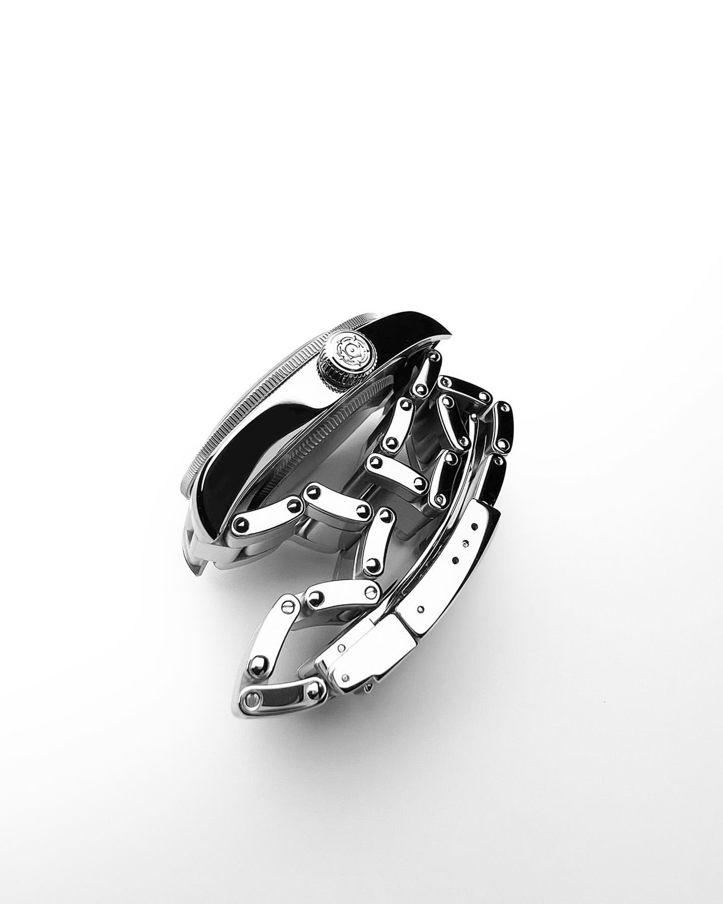 Monochrome studio shot of a stainless steel wristwatch with a link bracelet on a white background with soft, diffused lighting.