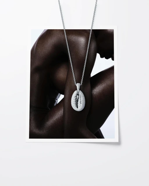 Glamorous fashion shot: A dark-skinned person wears a silver pendant necklace in a studio, accessorizing against a white background.