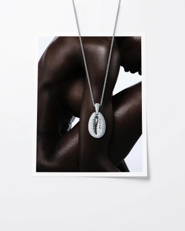 Glamorous fashion shot: A dark-skinned person wears a silver pendant necklace in a studio, accessorizing against a white background.