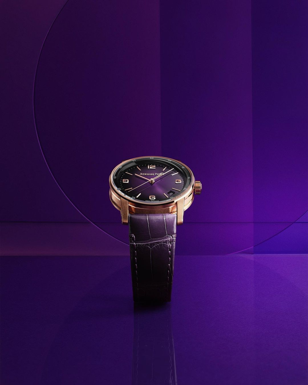 Elegant gold wristwatch with a purple face and alligator leather strap, displayed against a graduated purple background with geometric lines.