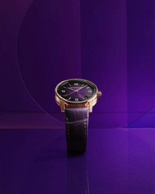 Elegant gold wristwatch with a purple face and alligator leather strap, displayed against a graduated purple background with geometric lines.