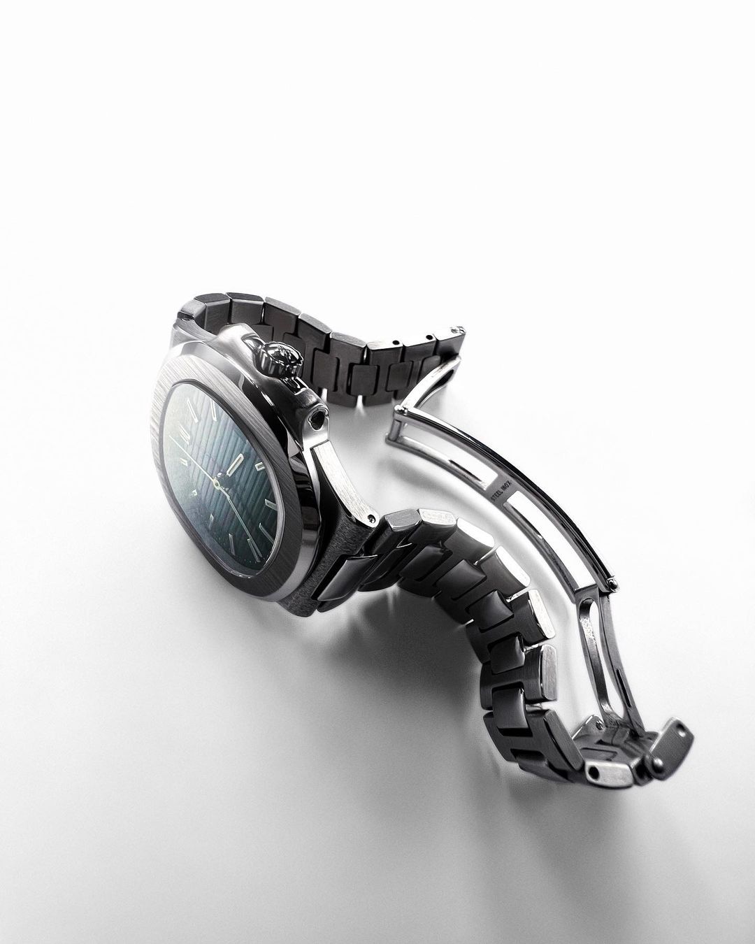 Studio shot of a modern wristwatch with a metal band on a white background, showcasing its design and craftsmanship.