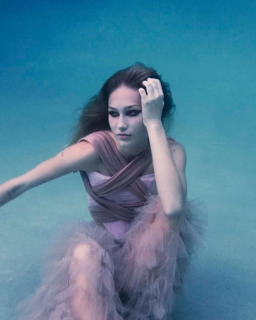 Underwater fashion portrait of a woman with long hair wearing a light purple dress in clear blue water with natural lighting.