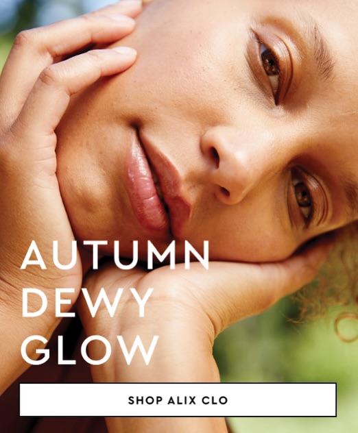 Close-up of a woman with dewy skin, her face framed by her hands, creating an autumn glow aesthetic. Beauty product advertisement.