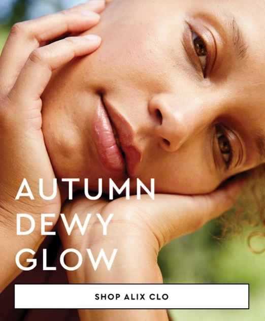 Close-up of a woman with dewy skin, her face framed by her hands, creating an autumn glow aesthetic. Beauty product advertisement.