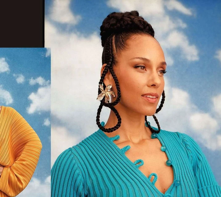 Close-up portrait of Alicia Keys, wearing a teal top and large floral earrings, against a backdrop of blue sky and white clouds.