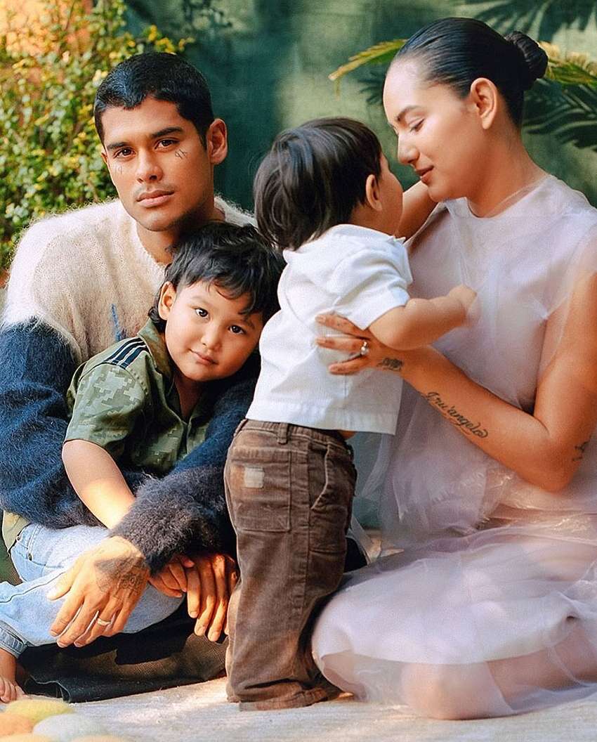 Family portrait features a mother, father, and two children together outdoors, showcasing their familial bond and connection in nature.