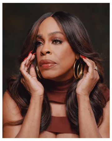 Close-up portrait of a Black woman with long dark hair, wearing large hoop earrings and a brown top, captured by Erik Carter.