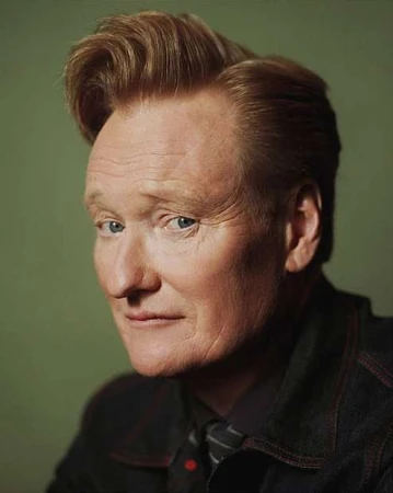 Portrait of Conan O'Brien with reddish-blonde hair wearing a dark jacket against a muted green background.