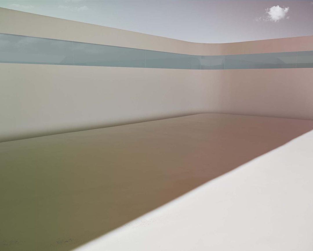 Minimalist shot of an empty room with sunlight creating a gradient on the floor, featuring a cloud visible through a horizontal window.