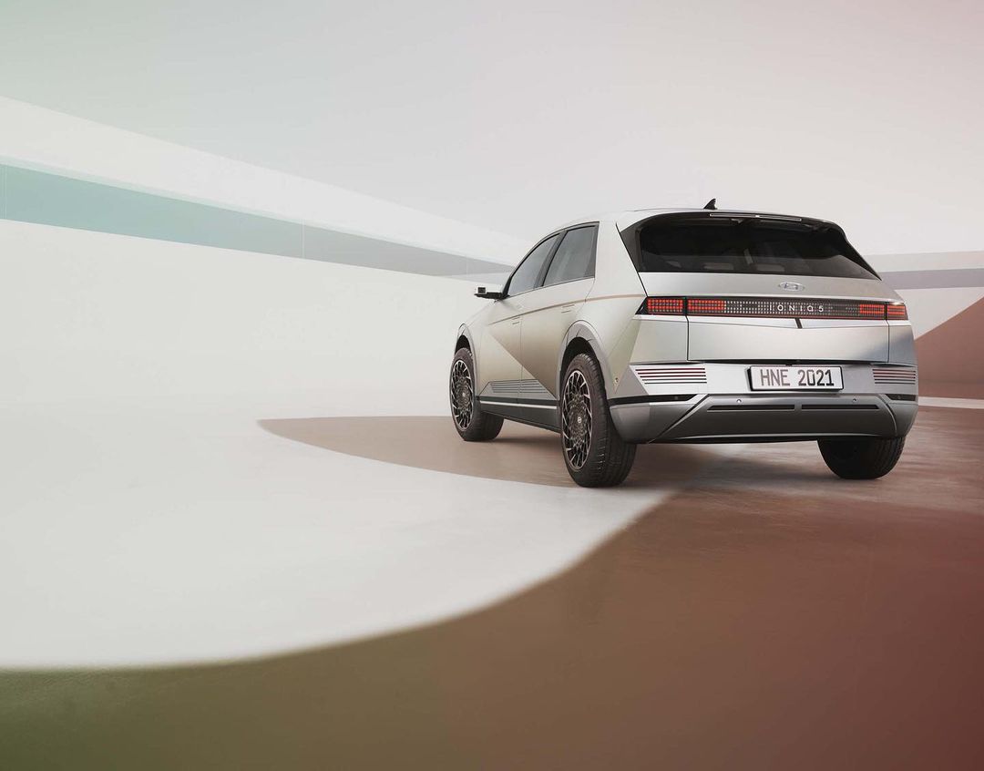 Silver Hyundai IONIQ 5 electric car, rear view, in a minimalist studio setting with smooth gradients on floor and wall.