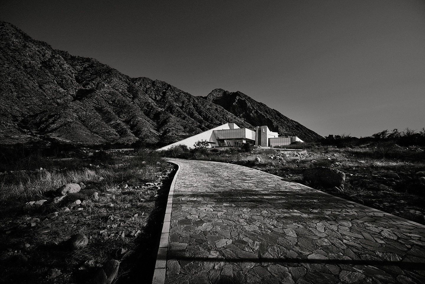 Monochromatic outdoor shot of a modern building near mountains, showcasing architectural design and natural landscape integration.