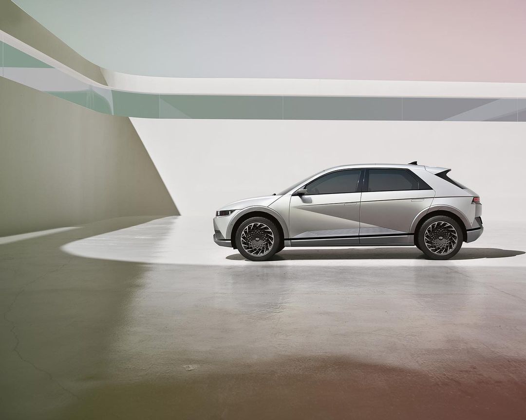 Silver Hyundai IONIQ 5 electric SUV parked in a minimalist architectural space with curved white walls and a polished concrete floor.