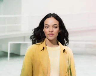 Portrait of a woman with dark wavy hair wearing a yellow coat by photographer Erik Chmil