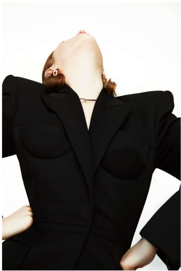 Model wearing a structured black blazer with padded shoulders against a white background by Erik Madigan Heck