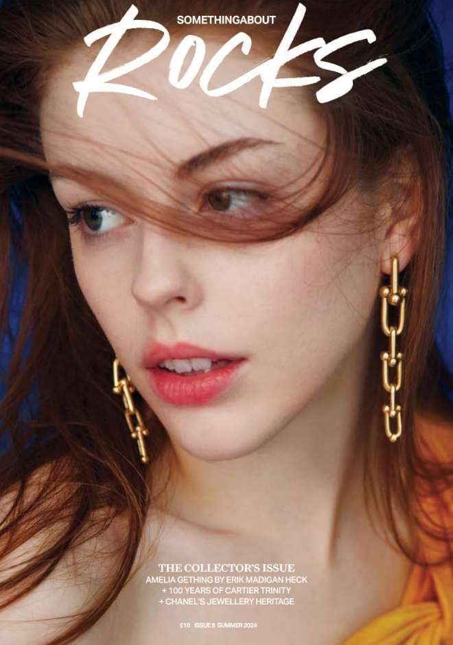 Magazine cover featuring a red-haired woman with gold chain earrings looking off to the side against a blue background.