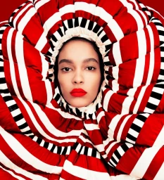 Portrait of a woman framed inside a large red, white, and black striped quilted collar with bright red lipstick