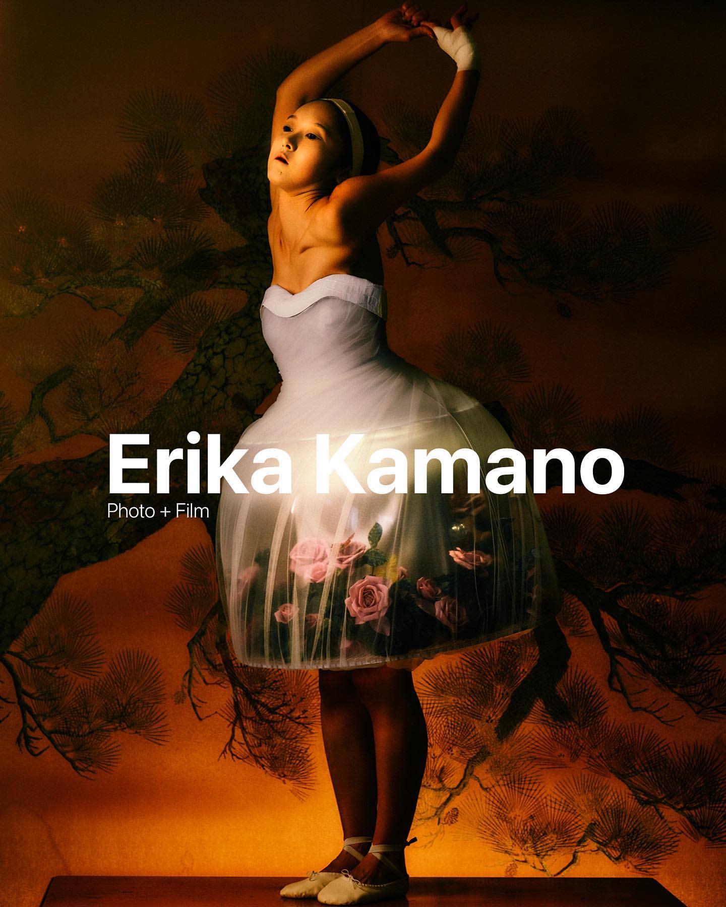 Full body portrait of girl in a white tutu dress, performing ballet on stage, against an orange backdrop with dark branches.
