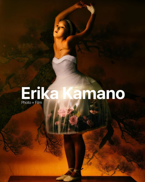 Full body portrait of girl in a white tutu dress, performing ballet on stage, against an orange backdrop with dark branches.