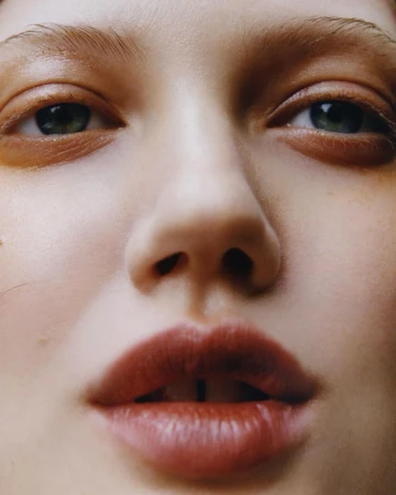 Extreme close up macro portrait of a model face focusing on eyes and lips with warm glossy skin tones by Erika Long.