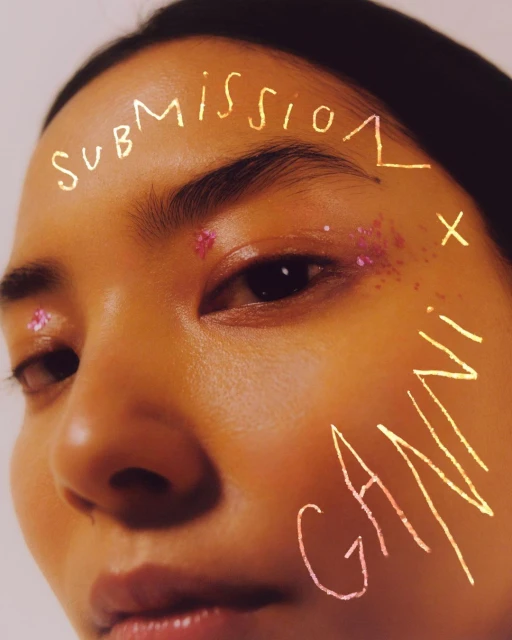 Close-up portrait of an Asian female adult with glitter makeup, featuring stylized text, and a tan skin tone against a plain backdrop.